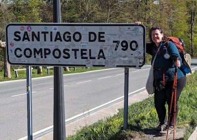 Krystin standing next to a road sign that says Santiago de Copostela 790